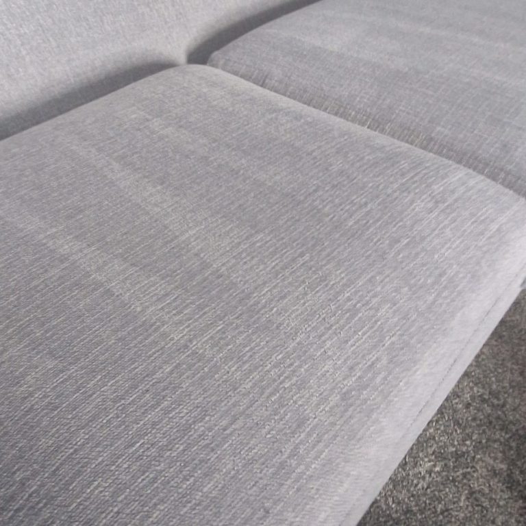 Close-up of a light grey fabric sofa cushion.